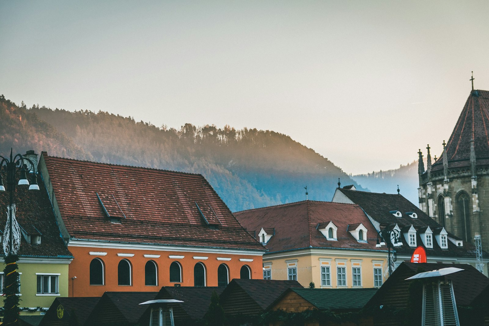Piața Sfatului din Brașov cu Biserica Neagră și muntele Tâmpa în fundal, terase și turiști